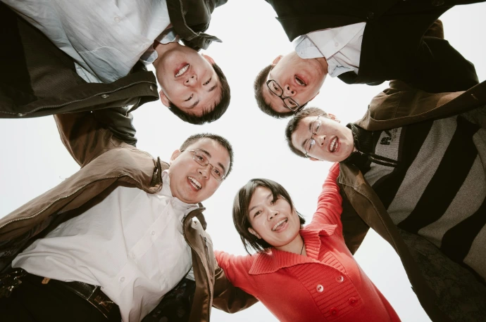 Five people in a circle looking down